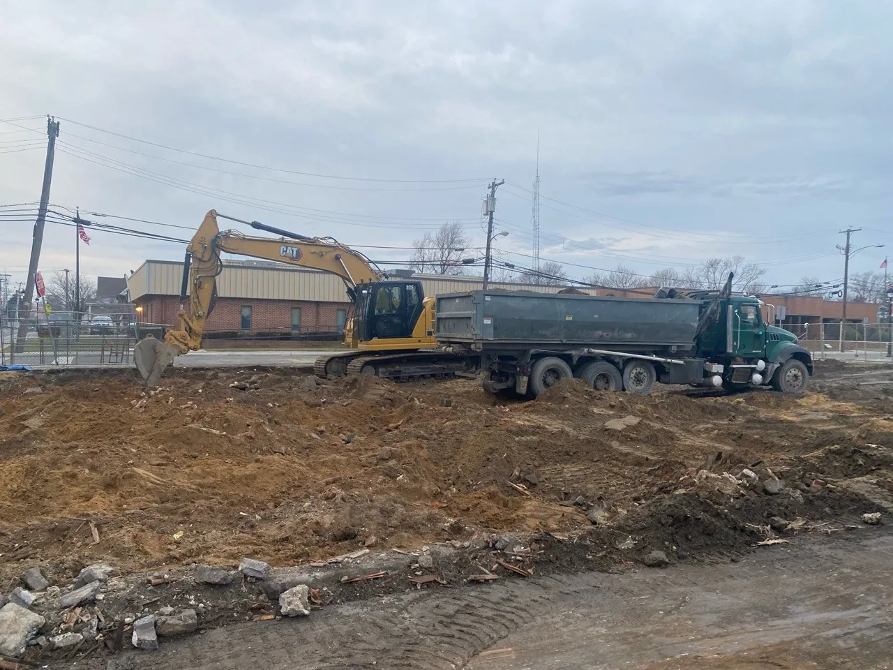 A construction site with an excavator and a dump truck on a dirt field.