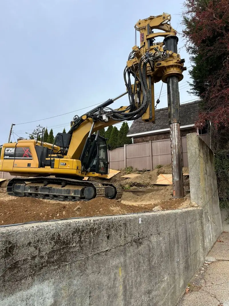 Yellow CZM foundation drilling rig operating on a residential site.